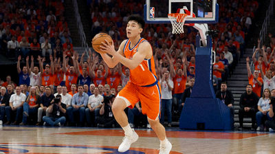 NBA篮球比赛中球员突破上篮的瞬间,体育馆内座无虚席,观众热情高涨